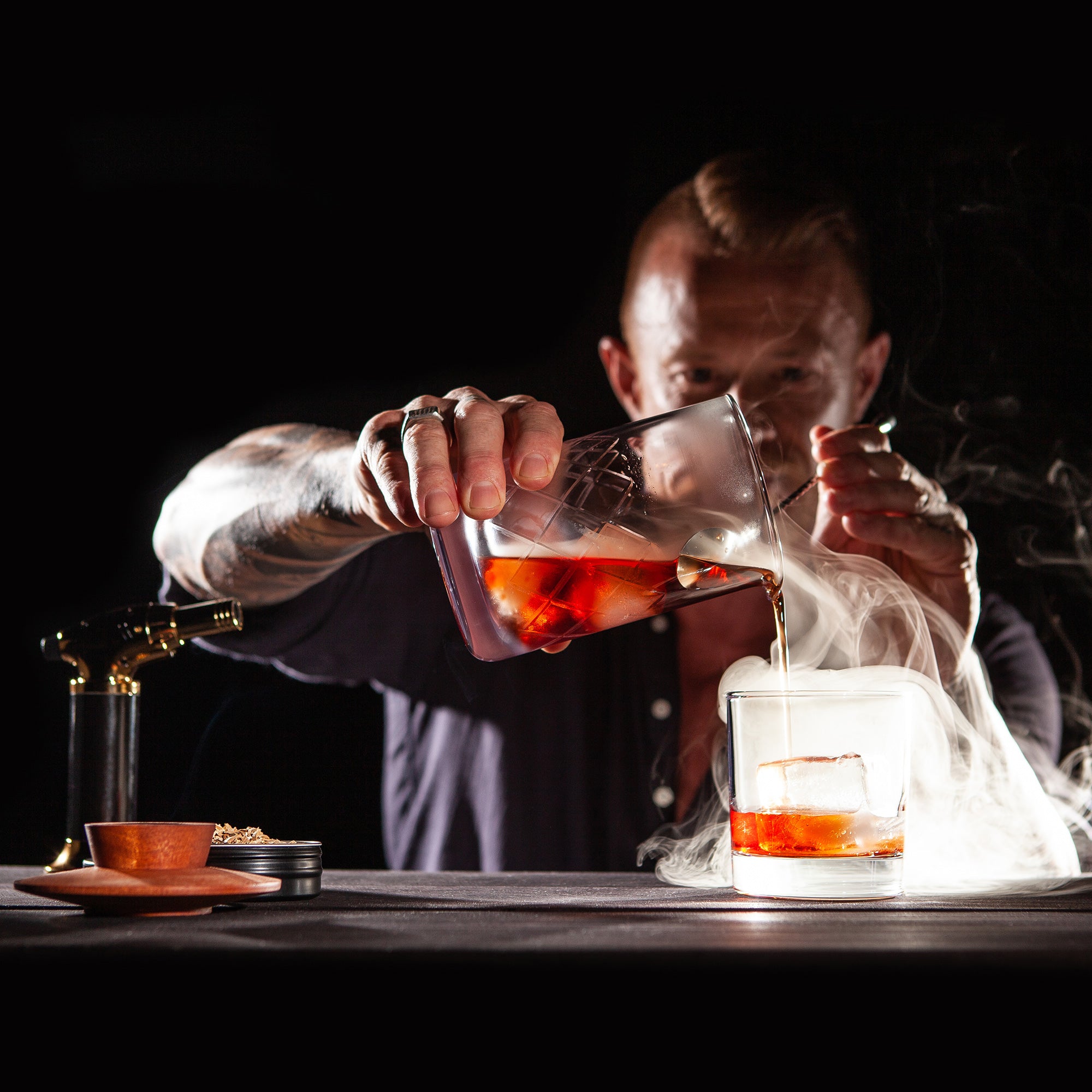 The Wild Fashion Cocktail being poured from a smoking mixing glass