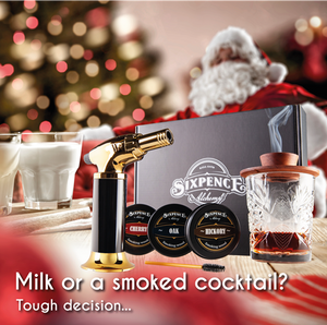 Sixpence Alchemy Cocktail Smoker on a Table With Santa sitting down offering it as the ultimate gift for men