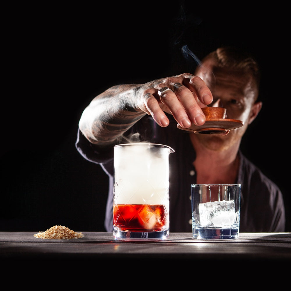 Man removing Sixpence Alchemy's single hardwood cocktail smoker from mixing glass