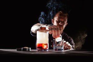 Mixing glass with a smoking Negroni cocktail and the Sixpence Alchemy hardwood smoker 
